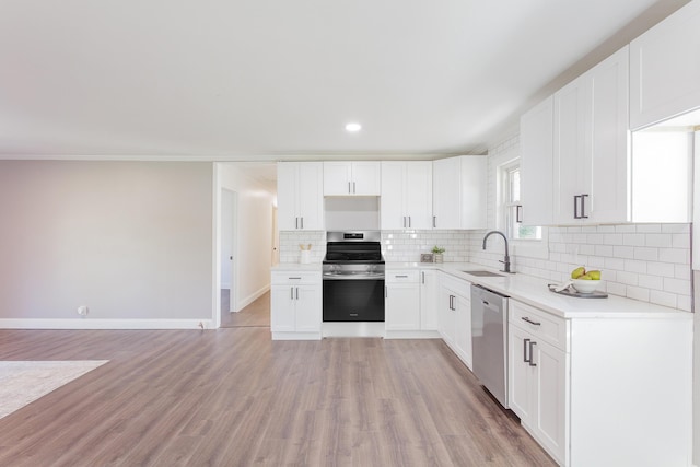 kitchen with light wood finished floors, light countertops, decorative backsplash, appliances with stainless steel finishes, and a sink