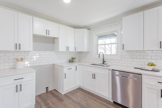 kitchen featuring white cabinets, dishwasher, backsplash, light wood-type flooring, and a sink