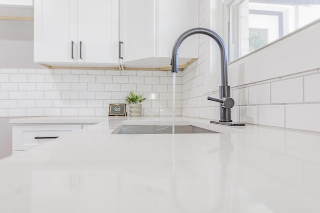 details featuring light countertops, a sink, white cabinetry, and decorative backsplash