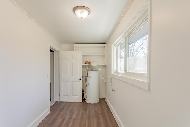 washroom featuring water heater, ornamental molding, dark wood-style flooring, and baseboards