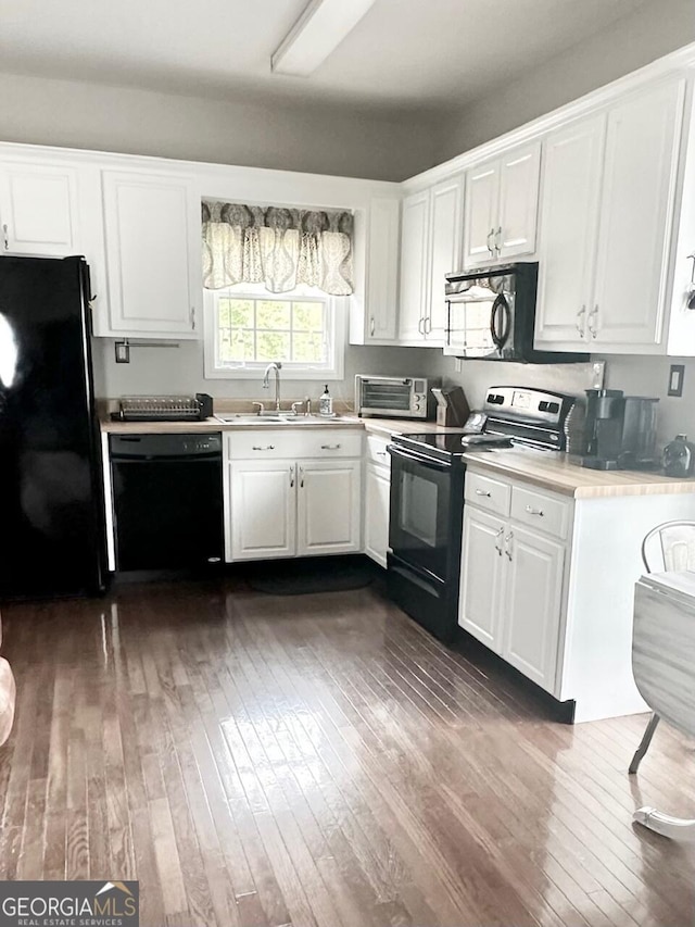 kitchen featuring dark wood-style floors, light countertops, white cabinets, a sink, and black appliances