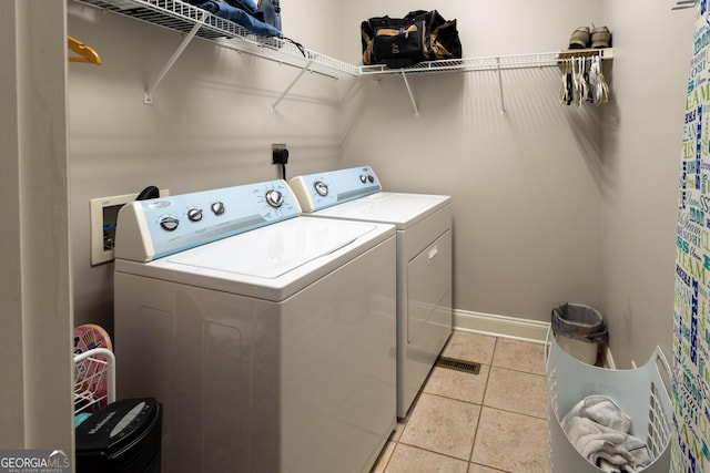 washroom with light tile patterned floors, laundry area, independent washer and dryer, and baseboards