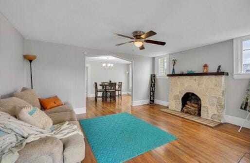 living area with a fireplace, plenty of natural light, wood finished floors, and baseboards