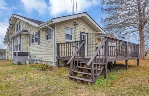 back of property featuring a lawn and a wooden deck