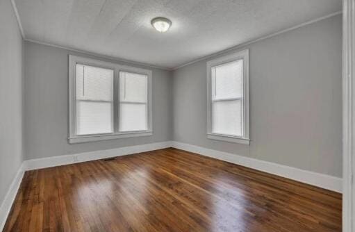 unfurnished room with baseboards, crown molding, and wood finished floors