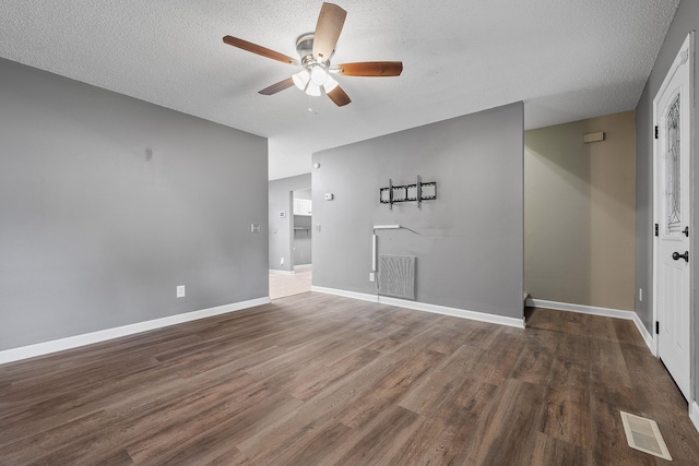 unfurnished room featuring visible vents, a textured ceiling, baseboards, and wood finished floors