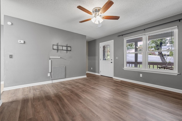 interior space featuring baseboards, a textured ceiling, visible vents, and wood finished floors