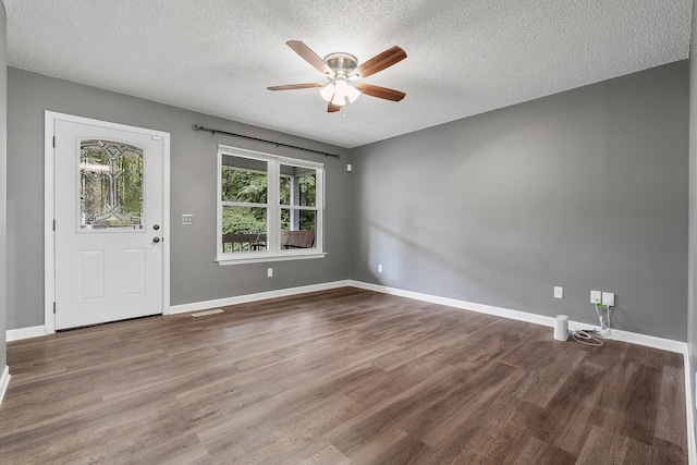 unfurnished room featuring a textured ceiling, wood finished floors, and baseboards