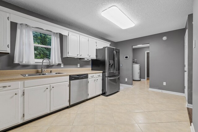 kitchen featuring electric water heater, a sink, white cabinetry, light countertops, and appliances with stainless steel finishes