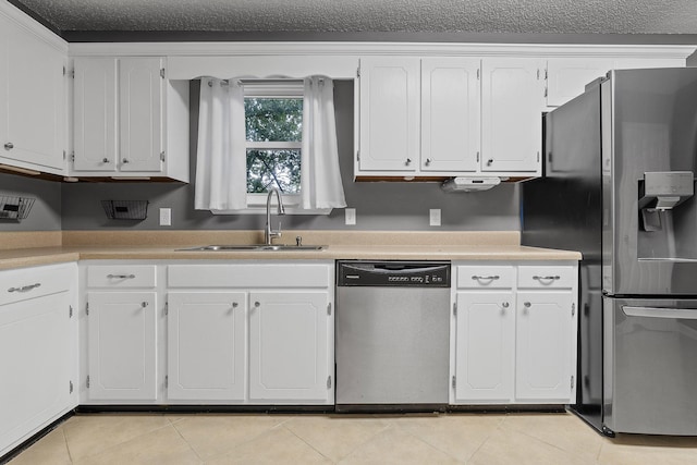 kitchen featuring white cabinets, stainless steel appliances, a sink, and light tile patterned flooring