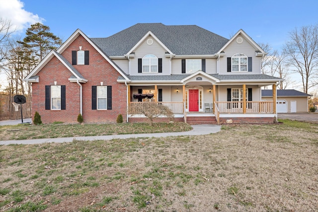 traditional-style home with a porch, a front yard, roof with shingles, and brick siding