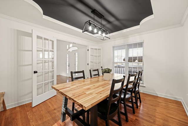 dining room with french doors, crown molding, baseboards, and wood finished floors