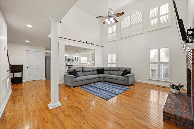 living area featuring ceiling fan, decorative columns, and light wood-style floors