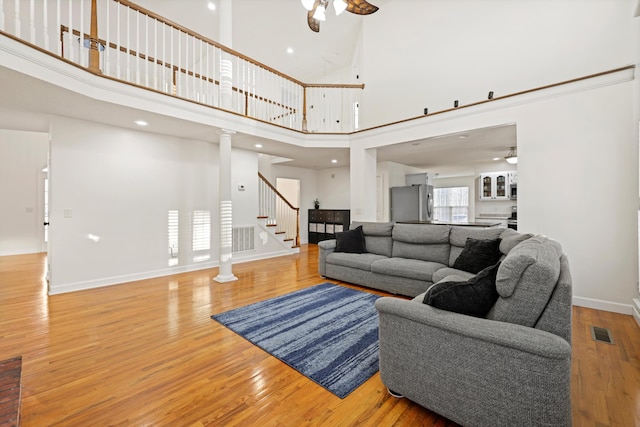 living room featuring stairs, visible vents, ceiling fan, and wood finished floors