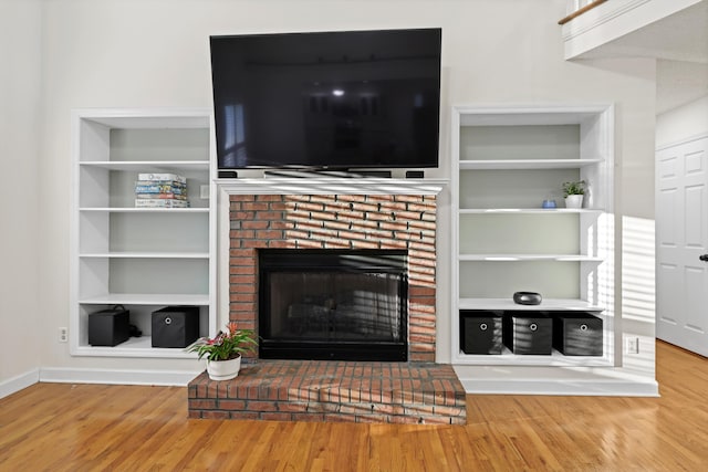 living area featuring built in features, a fireplace, and wood finished floors