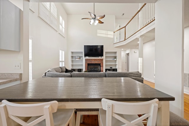 kitchen with dark countertops, a brick fireplace, a breakfast bar area, and wood finished floors