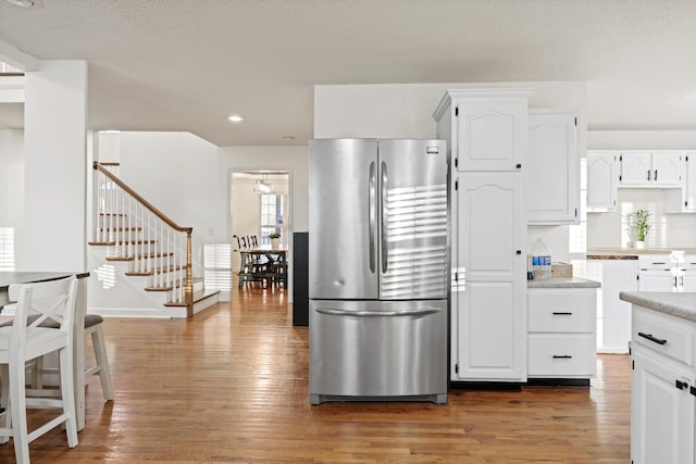 kitchen with light countertops, light wood-style flooring, freestanding refrigerator, and white cabinetry