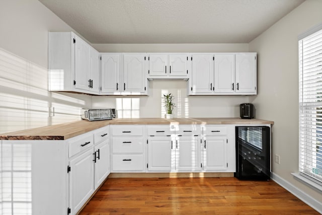 kitchen featuring light wood finished floors, wine cooler, and white cabinets