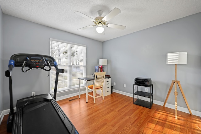 exercise area with visible vents, ceiling fan, a textured ceiling, wood finished floors, and baseboards