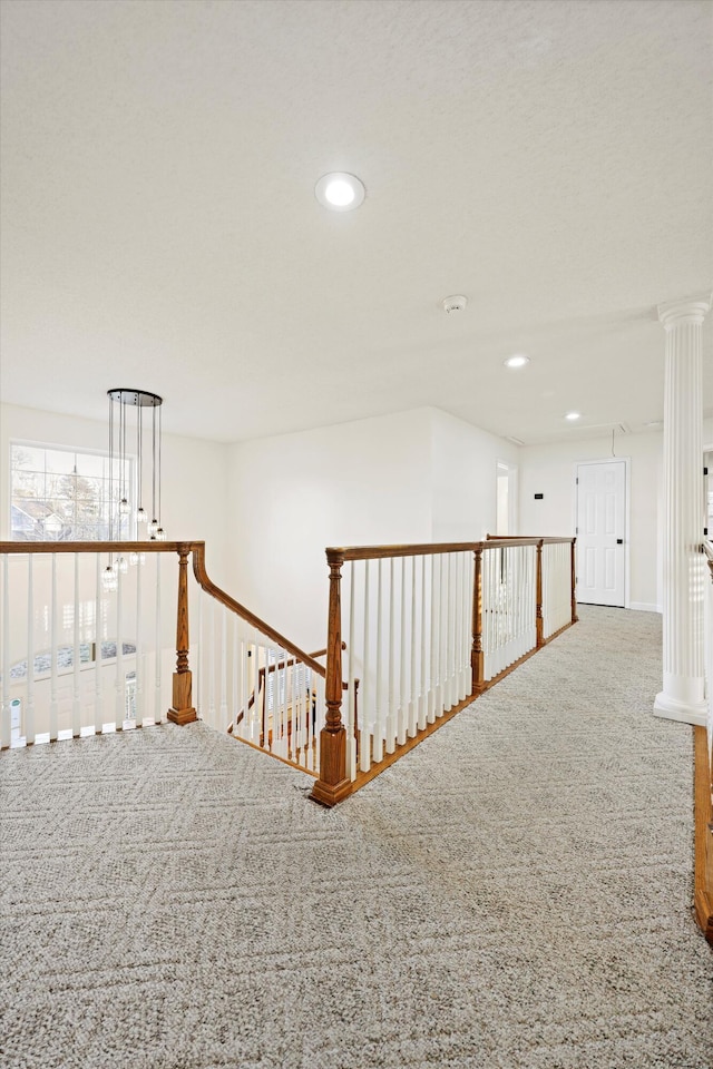 corridor with recessed lighting, ornate columns, carpet flooring, and an upstairs landing