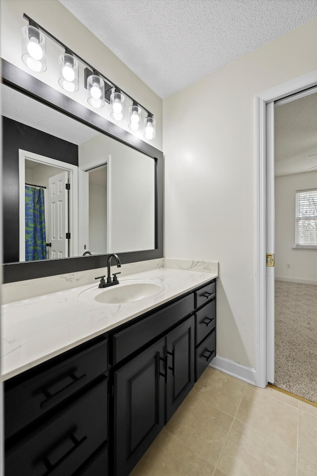 bathroom featuring vanity, baseboards, a textured ceiling, and tile patterned floors