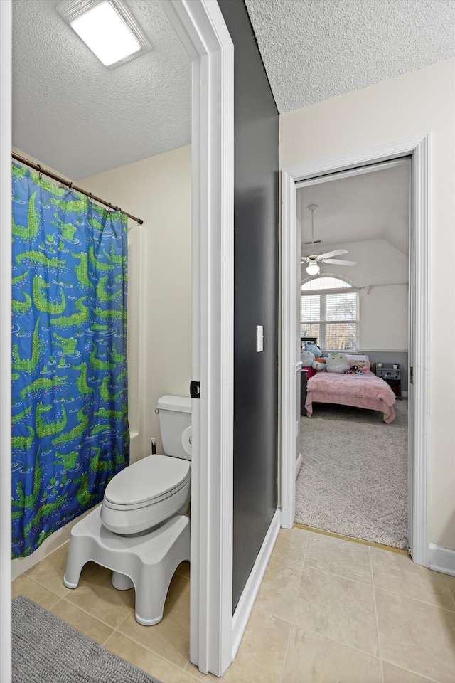 full bath with a shower with curtain, toilet, connected bathroom, a textured ceiling, and tile patterned flooring