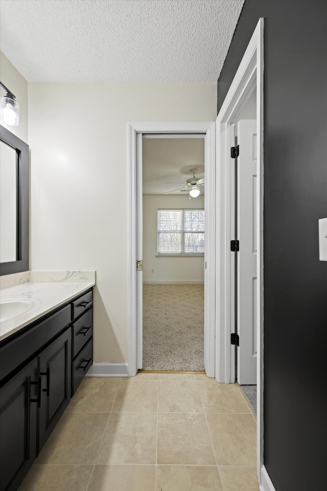 bathroom with ceiling fan, vanity, a textured ceiling, and tile patterned floors