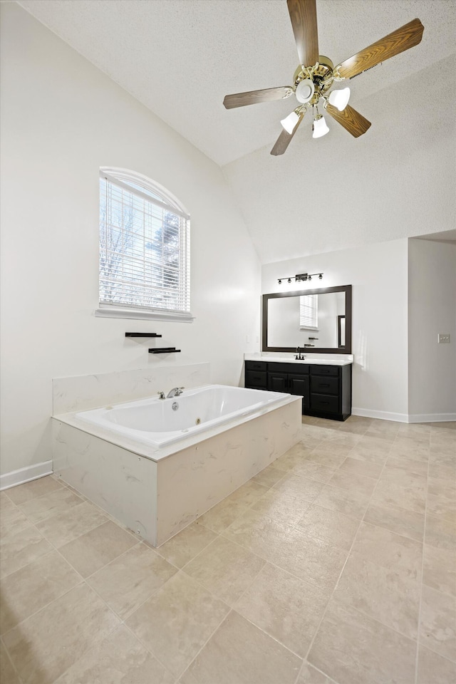 bathroom with lofted ceiling, baseboards, a jetted tub, and vanity