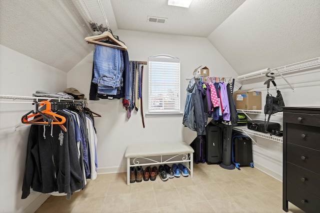 spacious closet with tile patterned flooring, visible vents, and vaulted ceiling