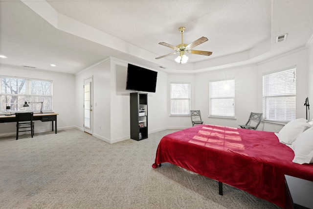 carpeted bedroom with ornamental molding, a tray ceiling, visible vents, and baseboards