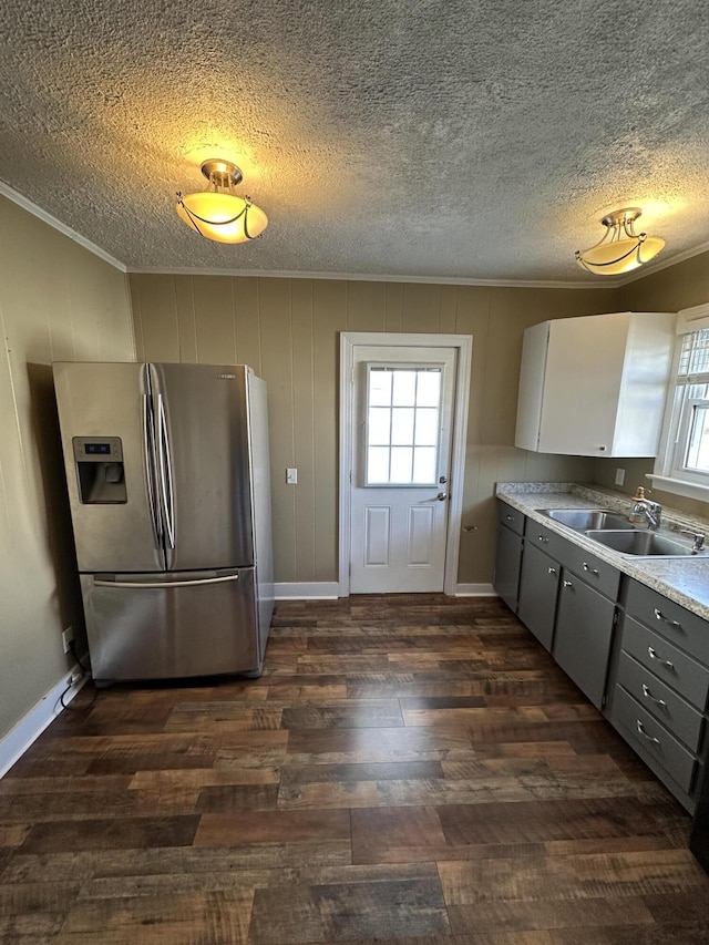 kitchen with dark wood finished floors, stainless steel refrigerator with ice dispenser, gray cabinetry, ornamental molding, and a sink