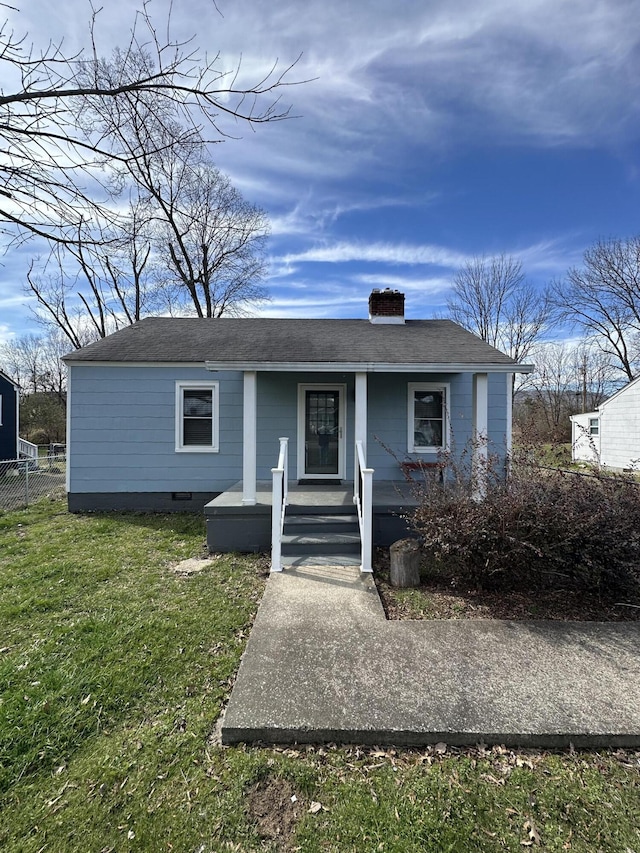 view of front of home with covered porch, fence, crawl space, a chimney, and a front yard