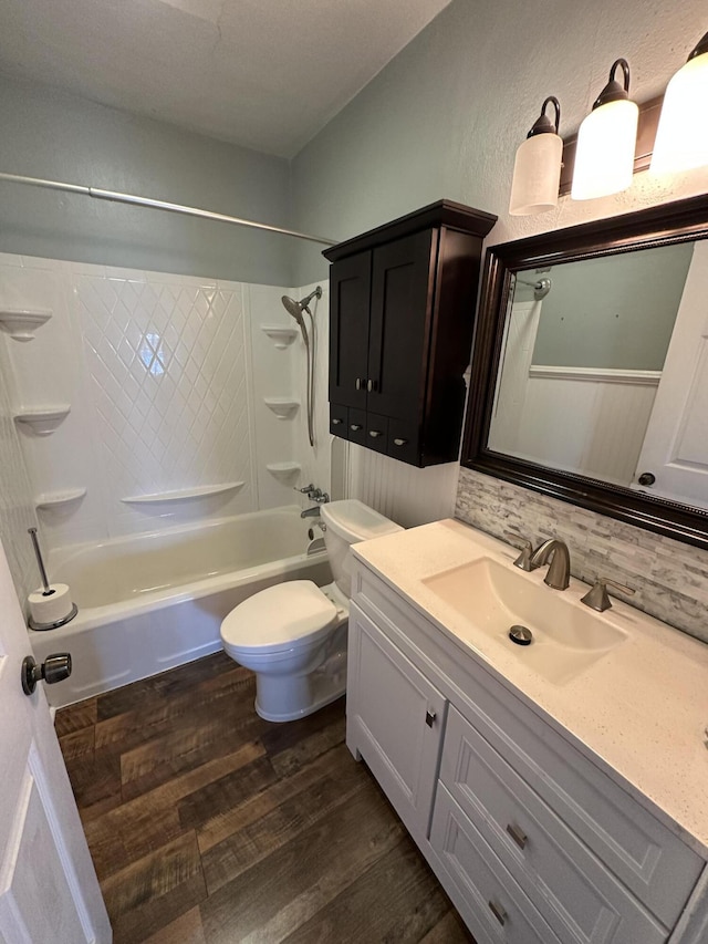 bathroom with toilet, wood finished floors, vanity, shower / bathing tub combination, and tasteful backsplash