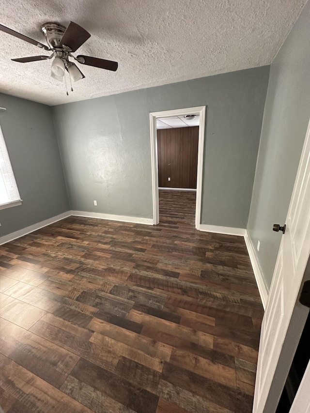 unfurnished room with dark wood-type flooring, a textured ceiling, baseboards, and a ceiling fan