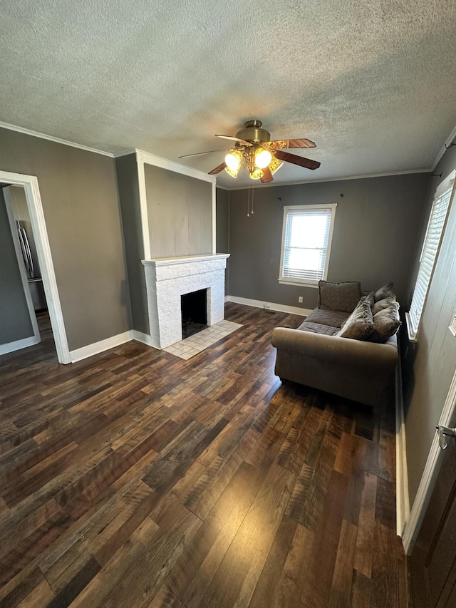 living area featuring baseboards, dark wood-style floors, ceiling fan, ornamental molding, and a brick fireplace