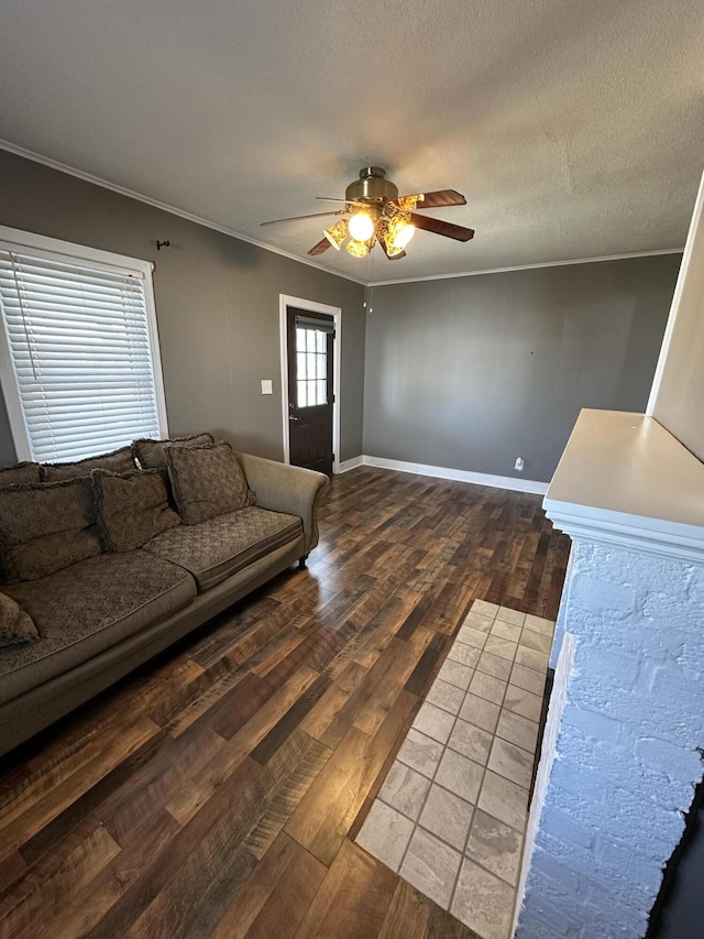 living area featuring ornamental molding, ceiling fan, a textured ceiling, wood finished floors, and baseboards