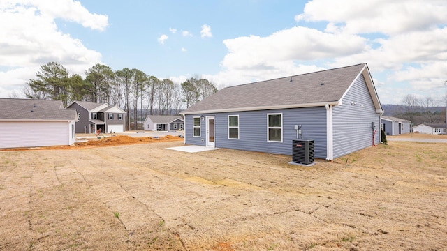 back of house with cooling unit, roof with shingles, a patio, and a residential view