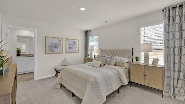 bedroom featuring baseboards, connected bathroom, visible vents, and light colored carpet