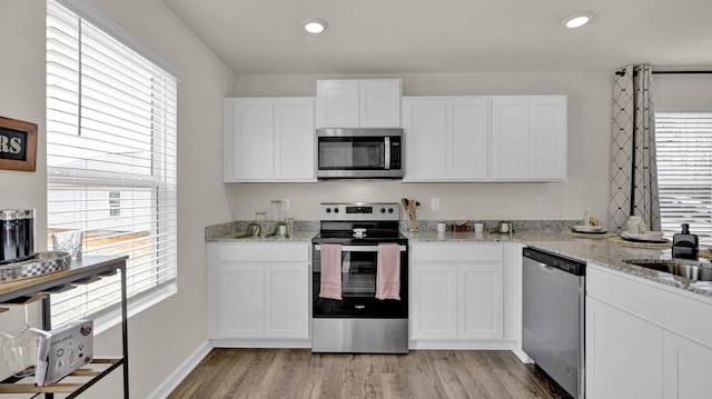 kitchen featuring light stone counters, recessed lighting, appliances with stainless steel finishes, light wood-style floors, and white cabinetry