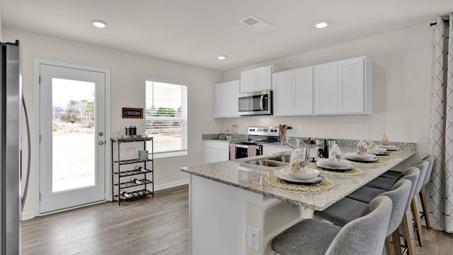 kitchen with visible vents, white cabinetry, stainless steel appliances, and a breakfast bar area