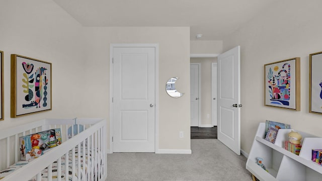 bedroom with light carpet, baseboards, and a crib