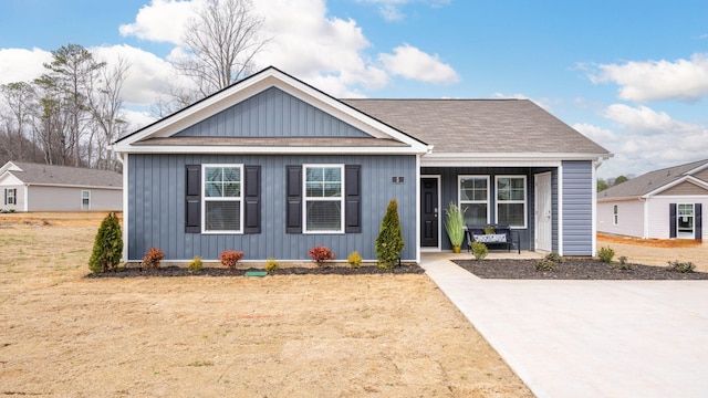 view of front facade with board and batten siding, a front yard, and covered porch