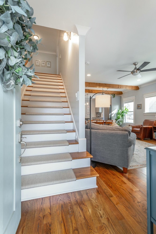 stairway with a ceiling fan and wood finished floors