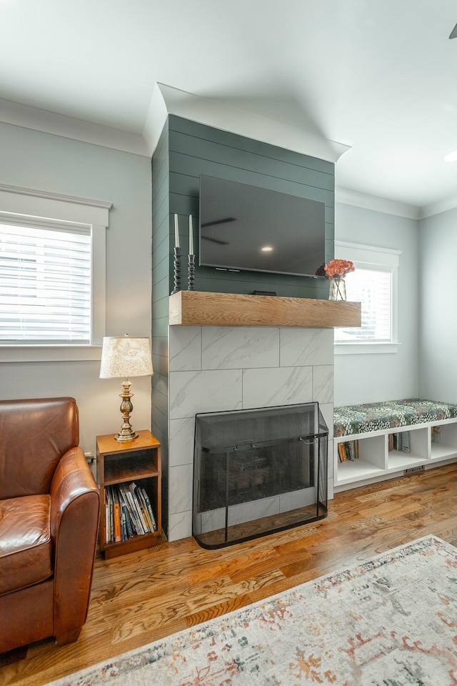 room details featuring a tiled fireplace, ornamental molding, and wood finished floors