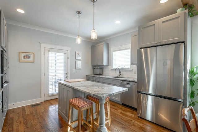 kitchen with dark wood-style flooring, a sink, appliances with stainless steel finishes, gray cabinets, and tasteful backsplash