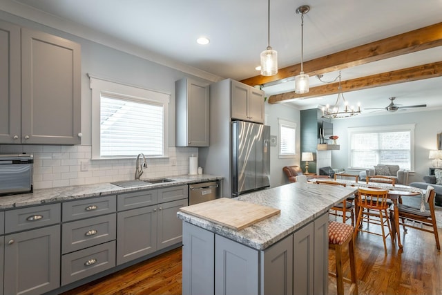 kitchen with appliances with stainless steel finishes, gray cabinets, a sink, and open floor plan