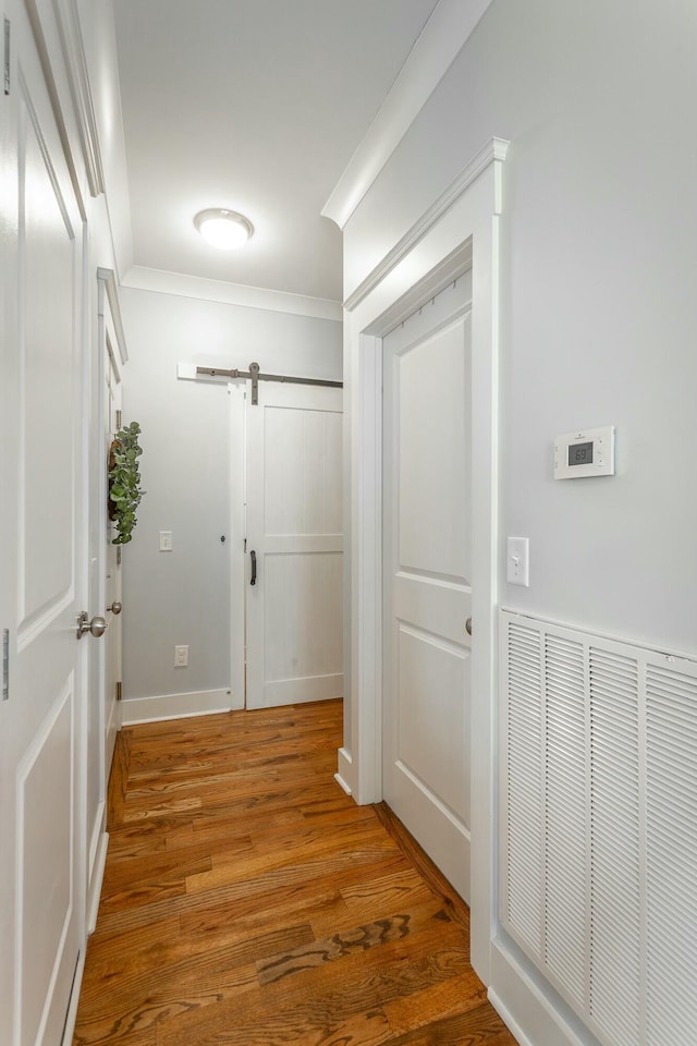 hallway with a barn door, visible vents, and wood finished floors