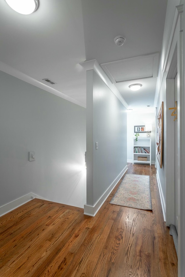 hall featuring visible vents, attic access, ornamental molding, wood finished floors, and baseboards