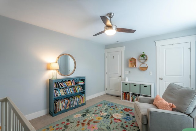 sitting room with baseboards, a ceiling fan, and light colored carpet