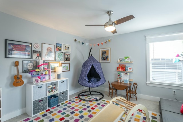 playroom with a ceiling fan, light colored carpet, and baseboards